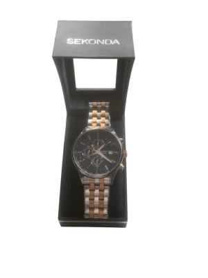 Sekonda klocka i silver och guld - Stilren klocka från Sekonda med svart urtavla och detaljer i guld. Armbandet är i metall med både silver- och guldfärgade länkar. Klockan har tre små urtavlor och datumvisning, perfekt för dig som gillar en klassisk men modern look.