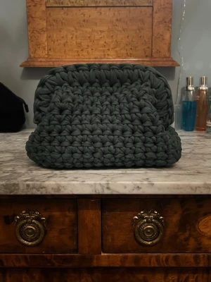 Virkad, mörkgrön clutch-väska - Säljer en egen-virkad clutch-väska! Den är i t-shirts material och i en mörkgrön färg. Se mått på bild! Skriv om du har frågor! :)