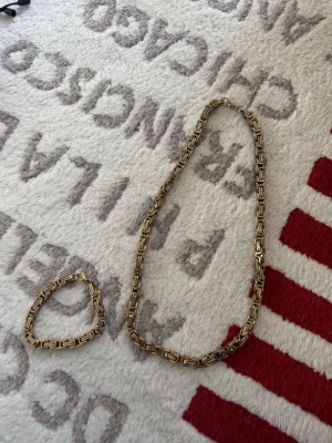 Chunky guldfärgat halsband - Säljer ett chunky halsband i guldfärg med rejäla, fyrkantiga länkar som ger en cool och trendig look. Halsbandet har en metallisk finish och passar perfekt för dig som vill sticka ut med accessoarerna. Märke och material är okänt.