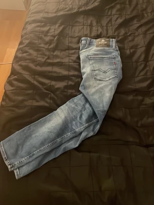 Blå jeans från Replay - Snygga blå jeans från Replay med klassisk femficksdesign och coola detaljer på bakfickan. Jeansen har en tvättad look och raka ben. Perfekta för dig som vill ha en avslappnad men trendig stil. Materialet är mjukt denim som sitter skönt hela dagen. Storlek 33 waist 30 length.