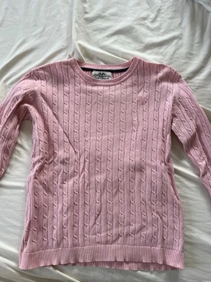 Rosa kabelstickad tröja  - Säljer en ljusrosa kabelstickad tröja från Hampton Republic, storlek 146/152. Litet hål i ena ärmen men inget som syns tydligt💗