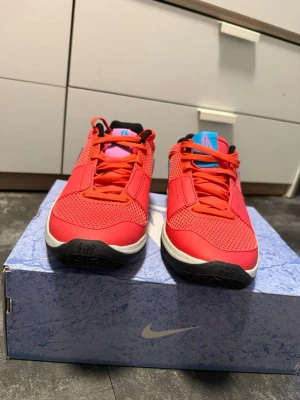 Nike Ja 1 Ember Glow - Snygga Nike Ja 1 Ember Glow basketskor i rött med blå detaljer och svart/vit sula. Ovandelen är i mesh och syntet för bra andningsförmåga och komfort. Helt nya, Ny pris 1783kr