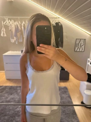 Vit linne med spetskant - Snyggt vitt linne med tunna axelband och söt spetskant längs urringningen. 🤍 Perfekt att styla till jeans eller shorts för en enkel och fräsch look. Mjukt och bekvämt material som känns skönt mot huden 🥰