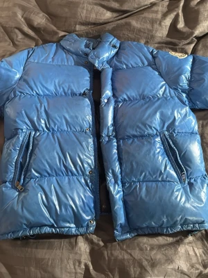 Blå moncler Everest Jacka - Blå äkta moncler Everest Jacka. Köpt på merchsweden på rea original pris 9000kr. Tekningen limmad på då den åkte av och lite sönder på armen men inget som är svårt att fixa. Passar mig perfekt som är storlek M/L