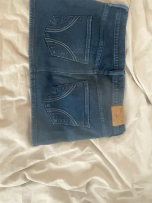 HOLLISTER KJOL storlek M - Säljer en mörkblå jeanskjol från Hollister med  snygga sömdetaljer på bakfickorna . 