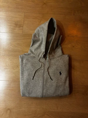 Polo Ralph Lauren zip - Säljer min ljusgråa Ralph Lauren hoodie med dragkedja. Klassisk modell som passar till allt och sitter jättesnyggt! Den ikoniska loggan är broderad i mörkblå på bröstet.                                                 Storlek: S  Skick: 9/10 (Väldigt fint skick)  Färg: Ljusgrå. Fraktar så snabbt som möjligt ! Skriv om du har frågor eller vill ha fler bilder.