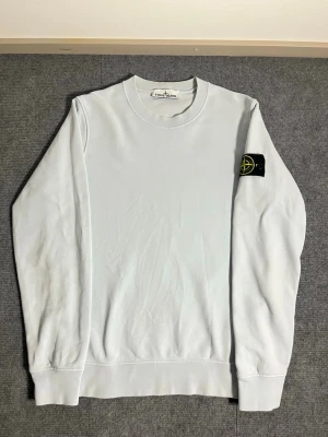 Stone Island – Light Blue Sweatshirt - size S  - Elegant and classic Stone Island sweatshirt in a refined light blue shade. Size S, length 67 cm, width 52 cm – fits perfectly for a modern, relaxed silhouette. The sleeve features the iconic Stone Island compass badge, symbolizing premium Italian craftsmanship and timeless design.  ✅ Condition: Excellent – no stains, no damage 💯 Authenticity: 100% genuine, can be verified easily on certilogo.com 📦 Shipping: Sent immediately after purchase – fast and reliable delivery!  This sweatshirt combines S