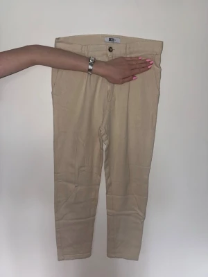 Beige chinos  - Snygga beige chinos med raka ben och klassisk passform. Byxorna har två sidofickor.