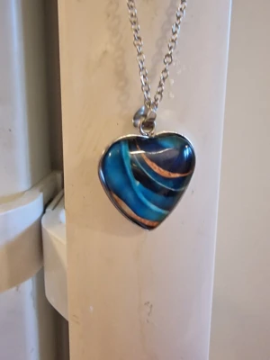 Halsband med hjärthänge multifärgat - Snyggt halsband med silverfärgad kedja och ett hjärtformat hänge med glasöverdrag. Hänget har ett motiv i olika färger. Kedja 45 + 5 cm. Berlock 2 × 2 cm.