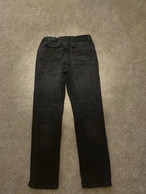 Svarta raka jeans med kontrastsömmar - Säljer ett par mörk gråa jeans från Jack and Jones storlek 152 skriv bara om du undrar något.