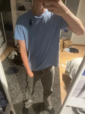 Ljusblå t-shirt från Ralph Lauren - Säljer en ljusblå t-shirt från Ralph Lauren med klassisk rund hals och korta ärmar. T-shirten har den ikoniska mörkblå polospelaren broderad på bröstet. Perfekt basic-plagg i mjuk bomull som funkar till det mesta.