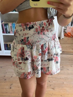 Blommig volangkjol från hm - Supersöt kort kjol med blommigt mönster i rosa, rött, svart och vit.  Storlek 146/152 från HM💕