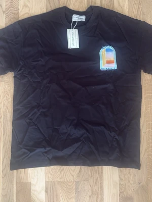 Svart Casa Blanca t-shirt med tryck - Snygg svart t-shirt från Casablanca med färgglatt fönstertryck och texten 'Casa Blanca' på bröstet och ryggen. Klassisk passform och rund halsringning. Perfekt för dig som vill ha en unik och trendig tee med cool grafik.