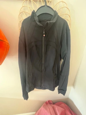 Svart zip-jacka från Lululemon - Snygg svart zip-jacka från Lululemon. Vet inte storleken eftersom att den är väldigt gammal och lappen ät inte kvar men skulle gissa på att det är runt storleken M. Inte så använd. Ser ny ut och det finns inga tecken på slitage 