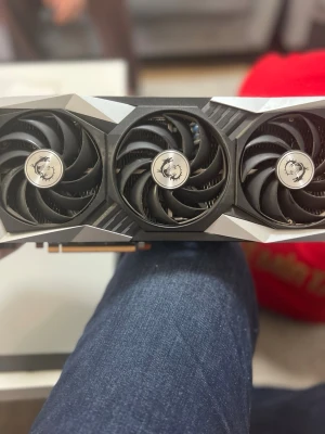 MSI Radeon RX 6800 Gaming X Trio 16GB - Grafikkort MSI Radeon RX 6800 Gaming X Trio med 16GB minne. Utrustad med tre stora svarta kylfläktar och silverdetaljer. Perfekt för gaming och tunga program. Robust design i metall och plast med MSI-logga på fläktarna.