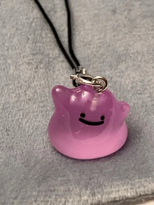 Ditto hänge pokopia charm pokemon nyckelring - Jättegulligt hänge med en Ditto! Den är dessutom självlysande och lyser i mörkret.   OBS just denna berlocken har några små repor på framsidan, därför säljer jag den till lägre pris.   Ditto-berlocken är ca 1,5 x 1,5 centimeter. Öglan är ca 5 cm lång.  Jättefin att sätta på din mobil, väskan eller i nycklarna exempelvis! Eller på ditt Switch eller DS. 