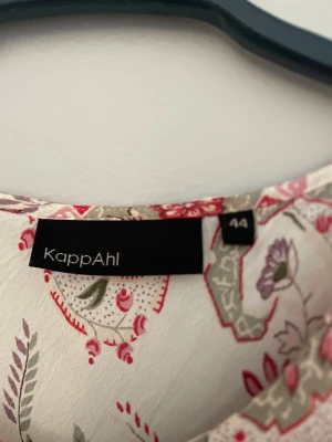Blommig ärmlös topp från KappAhl - Söt ärmlös topp från KappAhl i storlek 44. Toppen är vit med blommigt mönster i rosa, rött och grönt samt har en liten knytning framtill vid halsen. Perfekt för en fräsch och somrig look. Skulle nt påstå att den är i 44 själv r jag en s Elr m o den sitter perfekt