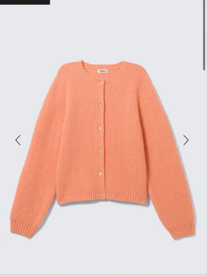 Persikofärgad stickad kofta från Monki - Mysig persikofärgad stickad kofta från Monki med rund halsringning och pärlemorknappar framtill. Den är i strl L men sitter som en M! Snygg då den är lite oversized och den funkar vardagligt🩵