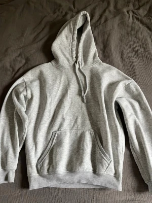 Grå hoodie - En jätteskön grå hoodie med huva och en stor magficka framtill. Den är använd men de märks inte på kvaliteten. De står xs men skulle säga att den är med S. 