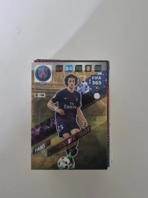 Samling fotbollskort FIFA 365 - Stor samling fotbollskort från FIFA 365-serien med olika spelare och lag, bland annat Paris Saint-Germain. Korten är färgglada och har detaljer som spelarstatistik och klubbmärken. Perfekt för dig som gillar att samla på sportkort eller vill byta med vänner.