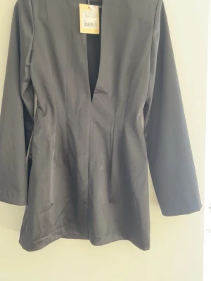 Långärmad klänning - Stilren svart klänning med lång ärm och djup v-ringning i ryggen . Klänningen ger en elegant look. Helt oanvänd med prislappen på