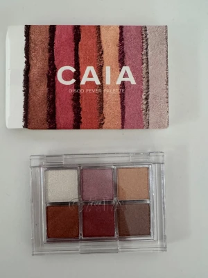 CAIA Disco Fever ögonskuggspalett - Oanvänd - Snygg ögonskuggspalett från CAIA med sex nyanser i varma toner som koppar, guld, vinröd, rosa, champagne och brun. Paletten har en genomskinlig plastförpackning och pigmentrika skuggor med både skimriga och matta finishar.