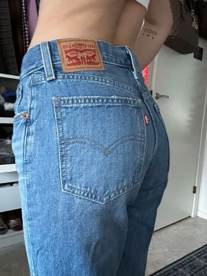 Levi's raka blå jeans - Klassiska blå jeans från Levi's med rak passform och medelhög midja. Jeansen har fem fickor, bälteshällor och den ikoniska läderlappen bak i midjan. Tillverkade i slitstark denim med en snygg ljusblå tvätt och röd Levi's-tag på bakfickan. Classy. Helt skadefria och relativt måttligt använda. 