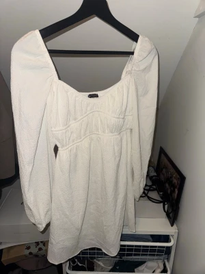 Vit kort klänning med puffärm - Vit klänning med långärmar. Använd en gång. Perfekt till skolavslutning eller student. Ifrån Bershka i storlek xs. 