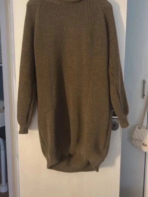 Olivgrön stickad oversized polotröja - Säljer en oversized olivgrön stickad polotröja med lång ärm och ribbade muddar. Tröjan har en längre, rundad bakdel och är perfekt för lager på lager. Mjuk och skön kvalitet, passar till många olika stilar.