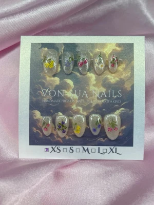 Flowers 💐(XS);Short Almond - Handgjorda press-on naglar med vit och glittrig bas och dekorerade med färgglada blommor i gult, lila, rosa, vitt och grönt. Naglarna har en kort almond form och varje nagel har unika blommotiv för en personlig look. XS: 14 mm, 11 mm, 11,5 mm, 10 mm, 8 mm , 