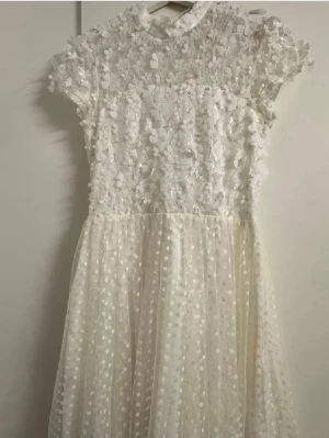 Vit Ida Sjöstedt spetsklänning med blommor - Vit spets klänning i begränsad upplaga för NAKD. Finns ej längre att köpa. Perfekt för studenten. Storlek: 36. 
