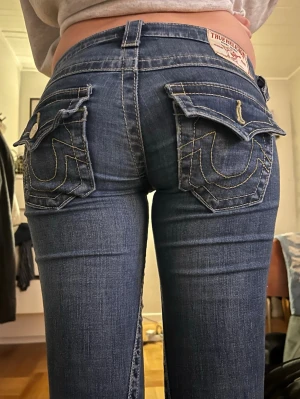 True religion Jeans lågmidjade  - Säljer mina sjukt snygga True Religion jeans i modellen ”Joey”🥰 De är lågmidjade med bootcut i storlek 24. Säljer då dom är lite för små och för korta på mig (170). Midjemått tvärs över: 38, innerben: 81💖 Inga defekter utöver att ena knappen på bakfickan har ramlat av men har kvar knappen och går nog lätt att så tillbaka eller bara sätta in i det hålet som är kvar🥰