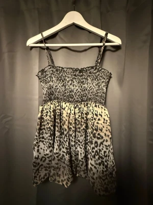 Smocktopp Leopardmönstrad - Säljer en smocktopp i leopardmönster med smala axelband och smockad överdel. Toppen har en luftig passform. Är också väldigt skön till sommaren då den har ett väldigt tunt material.