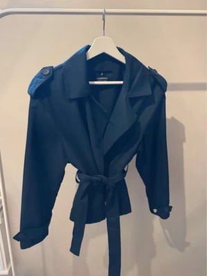 Mörkblå trenchcoat från Stradivarius  - Jackan har långa ärmar med remmar vid ärmsluten och en snygg cape-detalj på ryggen. Perfekt för dig som gillar tidlös och trendig stil🥂💗