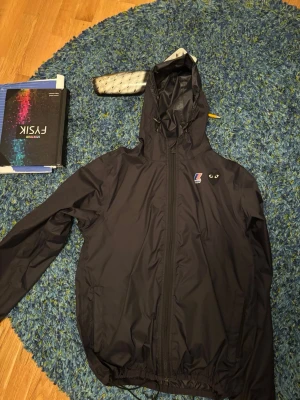 Svart vindjacka Comme des Garçons - Svart vindjacka från Comme des Garçons med huva och dragkedja framtill. Jackan har två fickor, justerbar dragsko nedtill och ikoniskt hjärta med ögon på bröstet och ryggen. Den är köpt på NK för 2500 finns kvitto kommer dock ej med vid köp. Skriv vid minsta fundering och kom med prisförslag 