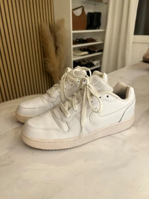 Vita Nike sneakers - Säljer ett par klassiska vita Nike sneakers i låg modell och matchande vita skosnören. Snygg och enkel design med diskret Nike-logga på sidan. Perfekta för dig som gillar stilrena och tidlösa sneakers. Använda ett fåtal gånger💕💕