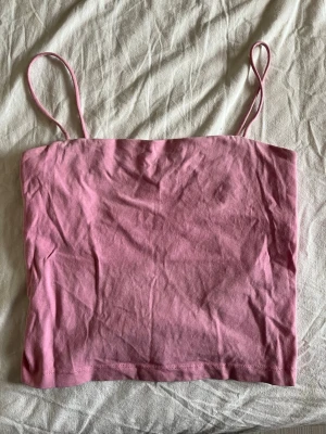 Rosa bandeau linnetopp - Söt rosa bandeau topp med tunna axelband och croppad passform. Perfekt till sommaren och enkel att matcha med jeans eller kjol. Tillverkad i mjuk bomull för en bekväm känsla.