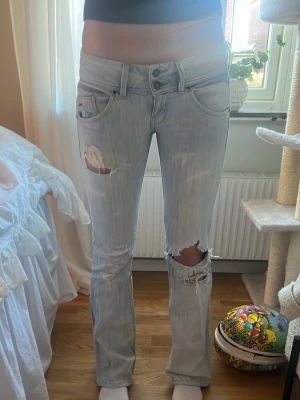 Ljusblå slitna bootcut jeans - Lite osäker på storleken men de är för stora på mig som oftas bär XS/34/25, midjemåttet tvärs över är 40cm, innerbenslängden 83cm