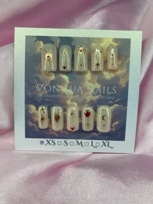 BraveHeart (XS);Short Square;Curved - Unika press-on naglar i nude bas med detaljer i guld, rött och vitt. Motiven inkluderar hjärtan, stjärnor, måne och gnistrande linjer. Naglarna har en kort,  square form och är handgjorda för en exklusiv look.XS: 14 mm, 11 mm, 11,5 mm, 10 mm, 8 mm 