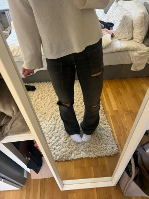 Svarta slitna bootcut jeans ifrån Gina Tricot  - Säljer ett par svarta bootcut jeans ifrån Gina tricot med slitningar över knäna och lätt utsvängda ben.  Finns en liten slitning längst ner. 😄