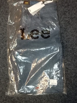 Blå jeans från Lee med rak passform - Säljer ett par klassiska blå jeans från Lee i rak modell. Jeansen är tillverkade i slitstark denim och har fem fickor samt knappgylf. Perfekta för dig som gillar tidlös stil och vill ha ett par jeans som funkar till allt.