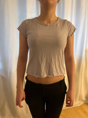 Gammel lila T-shirt  - Perfekt T-shirt att sova i, då materialet är väldigt skönt. Men man kan såklart ha den dagtid också. Gjord för barn, med en liten rosett framtill, lite vågig i ärm kanterna och i ”midjeöppningen”