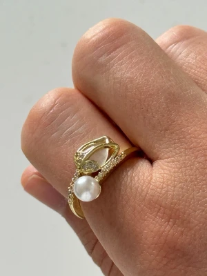 Guldring med pärlor - Unik guldring med små vita pärlor som dekoration. Ringen har en klassisk, tunn design och pärlorna sitter i en rad längs ovansidan. Perfekt för dig som gillar stilrena och eleganta smycken med en twist.