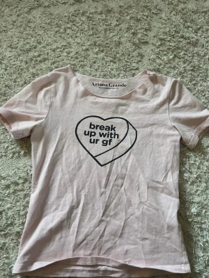Rosa Ariana Grande t-shirt - Ljusrosa t-shirt från Ariana Grande med svart tryck i form av ett hjärta och texten 'break up with ur gf' på bröstet. Klassisk rund halsringning och korta ärmar. ❣️