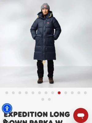 Fjällräven Expedition lång dunjacka - Lång dunjacka från Fjällräven med huva och gula detaljer. Jackan är mörkgrön, har stora fickor framtill och ett klassiskt Fjällräven-märke på bröstet. Perfekt för kalla vinterdagar med sin rejäla längd och värmande material. Använd i en vinter och är köpt december 2025 så knappt 4 månader gammal. Inköpt för 9000kr men absolut minsta jag kan tänka mig sälja för är 7600kr💗 Storlek S