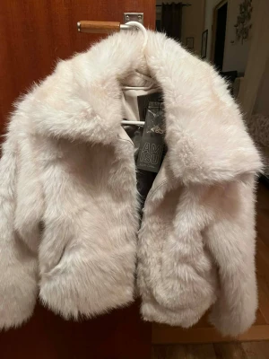 Vit jacka från Amisu med prislapp kvar - Säljer en fluffig vit jacka från Amisu med bred krage och två sidofickor. Jackan har en kortare modell och stängs framtill. 