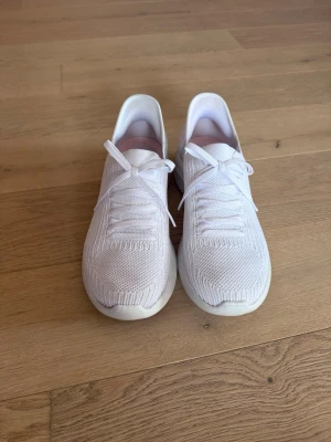 Vita Skechers Slip-ins sneakers - Helt nya! Fräscha vita sneakers från Skechers Slip-ins med stickad ovandel och klassisk snörning. Skorna har en låg profil och mjuk, flexibel sula som ger skön komfort. Perfekta för dig som gillar stilrena och bekväma sneakers i vardagen.