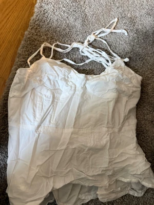 Vit linnetopp med knytband - Säljer en vit linnetopp med tunna axelband som knyts upptill. Toppen har en luftig passform och är tillverkad i ett lätt tyg, perfekt för varma dagar. Enkel och stilren design som passar till det mesta. Otroligt skrynklig på grund av nedpackad vid flytt. Populära fina linnet från shein 