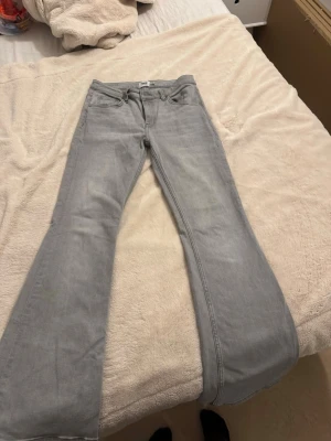 Ljusgrå bootcut jeans - Säljer ett par ljusgrå bootcut jeans från Lager 157 Jeansen har klassisk femficksmodell, hög midja och vida ben. Tillverkade i mjuk denim med en snygg tvättad look. Perfekta för dig som gillar en avslappnad men trendig stil.