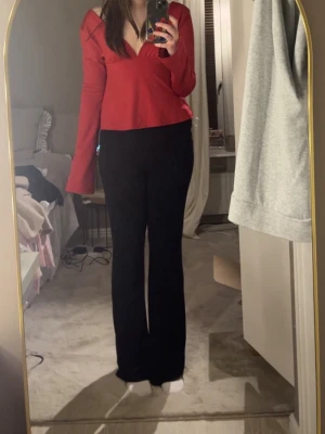 Röd topp med öppen rygg- Nelly - Trendig röd långärmad topp med djup v-ringning framtill och snygg öppen rygg. Toppen har en figurnära passform och är tillverkad i ett mjukt, stretchigt material som sitter bekvämt. Perfekt för dig som vill sticka ut med en cool och modern look.